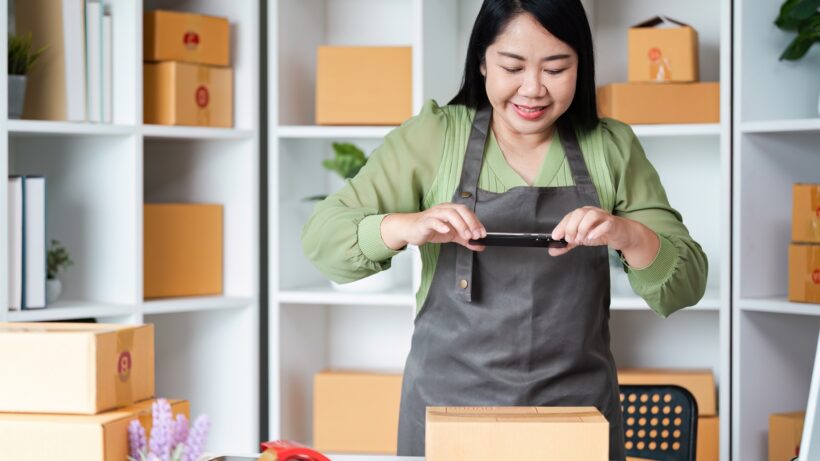 Small Business Owner Packaging Products in Office with Shelves and Boxes