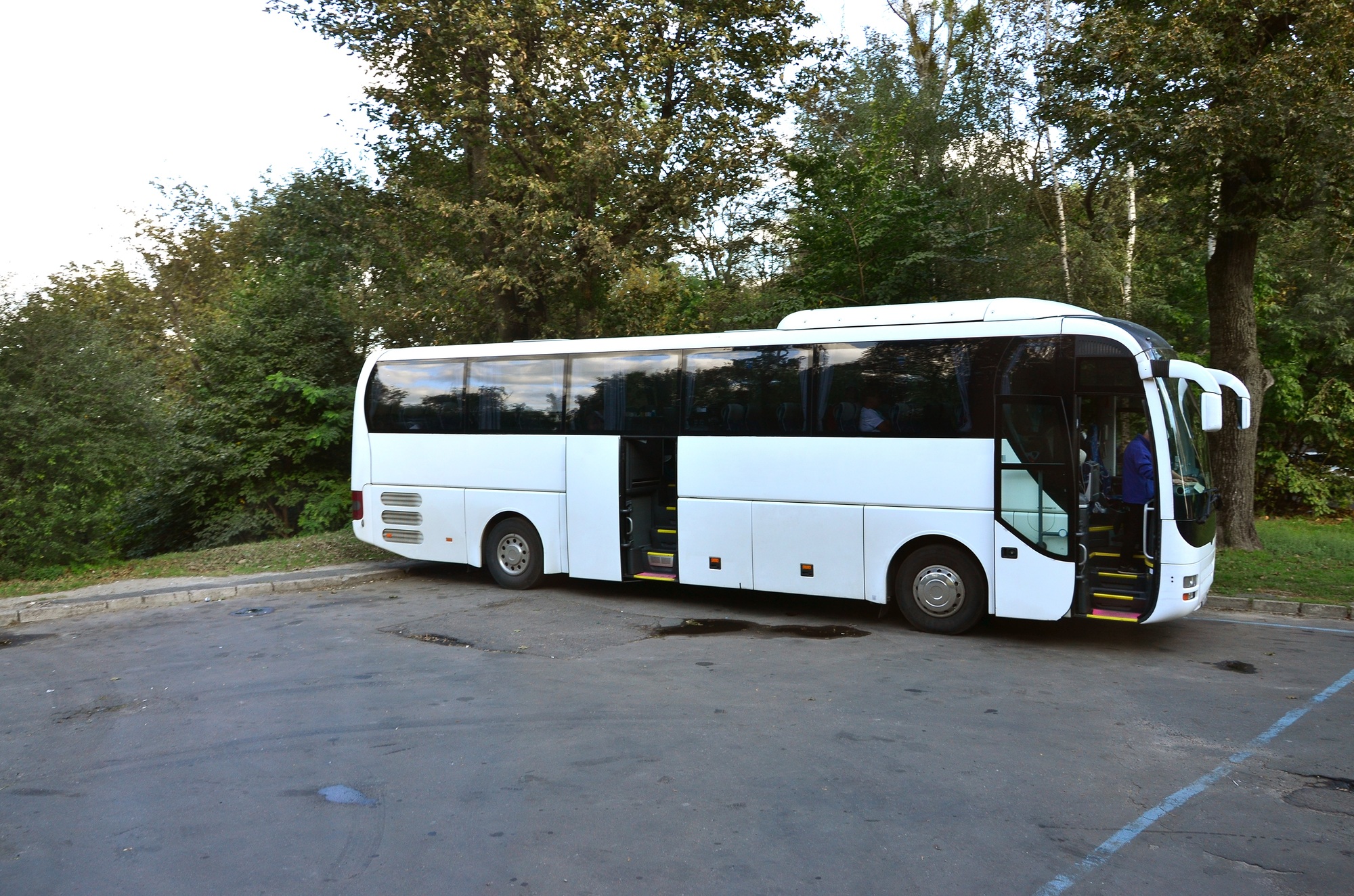 White tourist bus for excursions. The bus is parked in a parking lot near the park